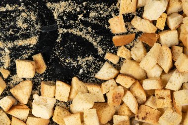 Siyah arka planda pişmiş krakerler. Yakın plan. Kurutulmuş küçük ekmek parçaları. Ekmek kırıntıları.