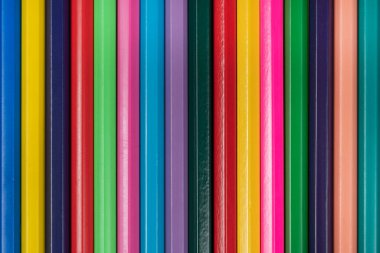 Ahşap renkli kalemlerin arka planı desenli. Büyük bir planda çok renkli bir kalem satırı