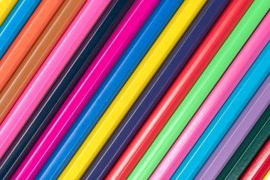 Ahşap renkli kalemlerin arka planı desenli. Büyük bir planda çok renkli bir kalem satırı