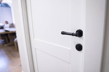 Siyah saplı beyaz ahşap kapı.