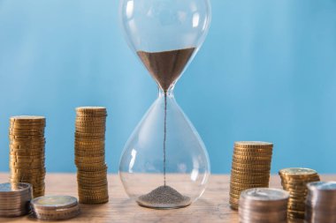 Mavi arkaplanda bozuk paralar olan kum saati