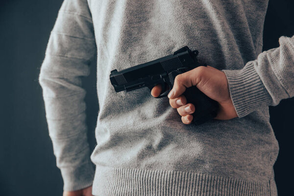 man hand gun in back on dark backgroun