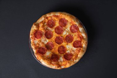 Büyük, parlak, sulu pizza, siyah sırtüstü.