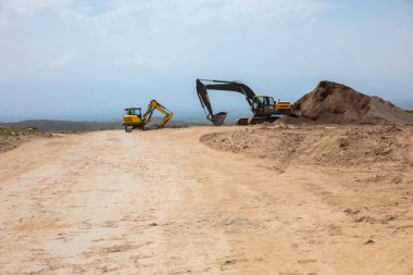 Büyük sarı çizgili bir kazıcı taş ocağında kaya çıkarıyor.
