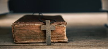 Holy Bible and wooden cross on wooden backgroun