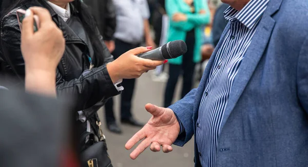 Journalists holding microphone, interviewing female speaker