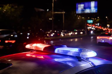 Şehir merkezinde gece polis arabasının ışıkları yanıyor.
