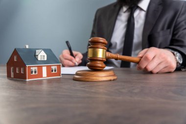 Auction, Real Estate concept. Hand with judge gavel and house mode