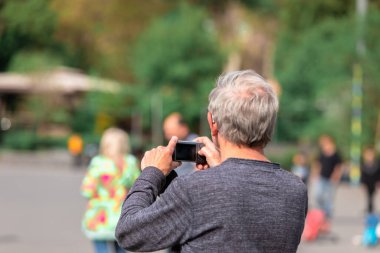 old man shooting photos in a par