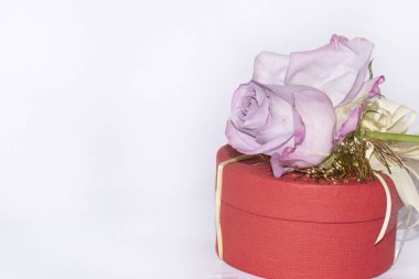 Beyaz arka planda kurdeleli ve çiçekli hediye kutusu