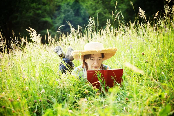 Chica leyendo un libro acostado en la hierba alta — Foto de Stock
