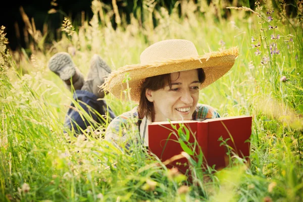 Dziewczyna czytająca książkę leżąc na trawie wysoki — Zdjęcie stockowe