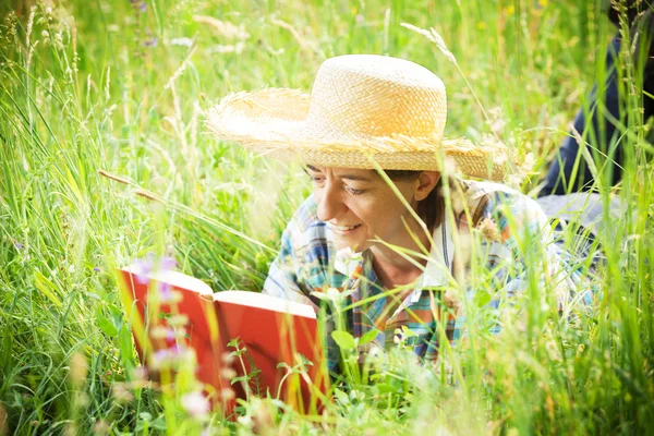 Chica leyendo un libro acostado en la hierba alta — Foto de Stock