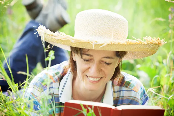 Chica leyendo un libro acostado en la hierba alta — Foto de Stock