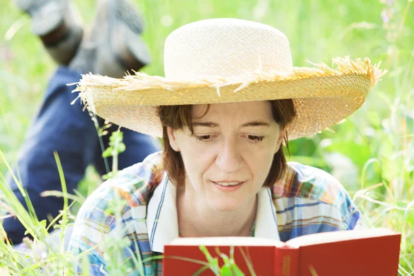 Flicka som läser en bok som ligger i det höga gräset — Stockfoto