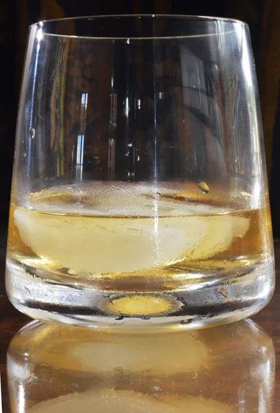 Um copo de uísque refletido na mesa — Fotografia de Stock