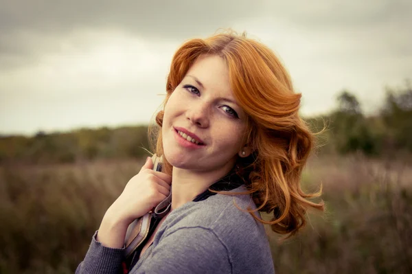 Portrait of a beautiful redhair girl in the autumn park. Royalty Free Stock Images