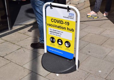 Covid aşı merkezi tabelası ve Brighton UK 'de insanlar sokakta kuyruğa giriyor..