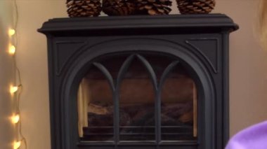  Sarışın bir kadın şömineye başlar ve Xmas bardağından çay içer..