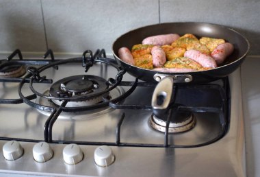  Sosisler ve sert kahverengiler gaz ocağında kızartılıyor..