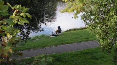 Person surrounded with nature is fishing by the river in England on a nice day.