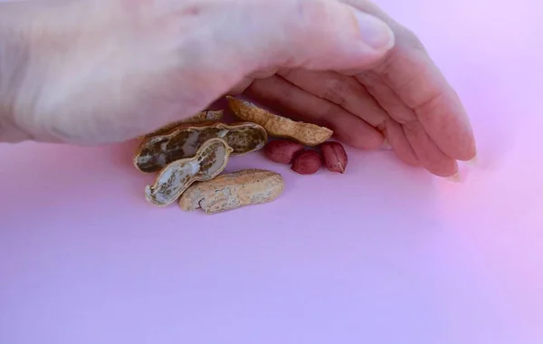 女性の手で光の背景にピーナッツ — ストック写真