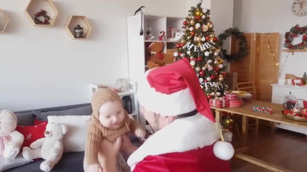 Kerstman Een Rood Witte Outfit Speelt Met Een Baby Tegen — Stockvideo