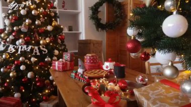 Noel pastaları, hediyeler ve süslü Noel ağaçlarının arka planında yanıp sönen ışıklar ve renkli toplarla dolu bir oyuncak tren.