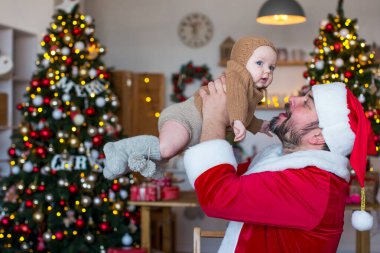 Noel Baba, Noel ağaçlarının arka planında onu kollarında tutan bir çocukla oynuyor.