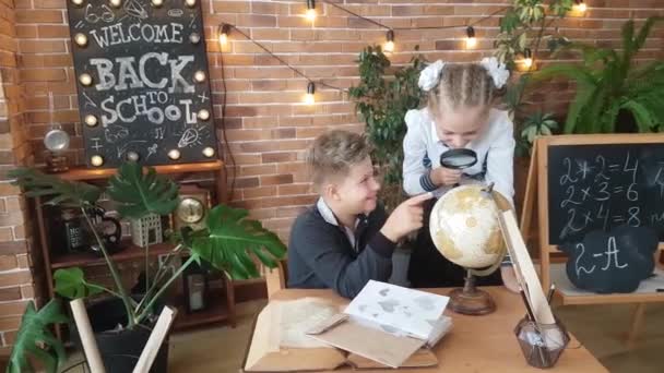 Uczniowie Chłopiec Dziewczynka Studiują Kulę Ziemską Szkłem Powiększającym Klasie Tle — Wideo stockowe