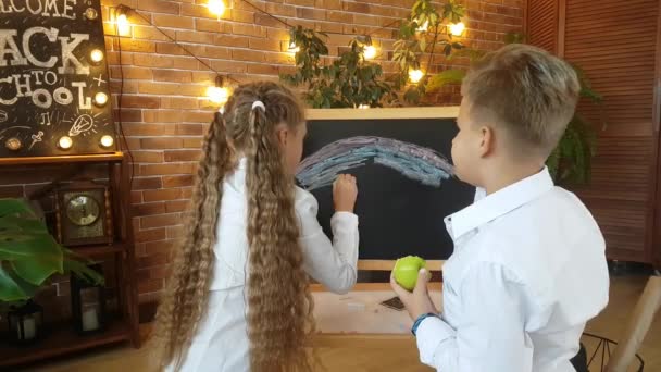 금발의 학생들 소녀가 비문등을 배경으로 칠판에 색깔의 크레용을 무지개를 학교로 — 비디오