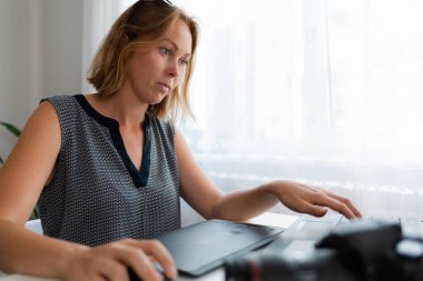 İş ve yaratıcılık. Genç bir kadın bilgisayarın başında çalışıyor. Kamera ve tabletin yanında..