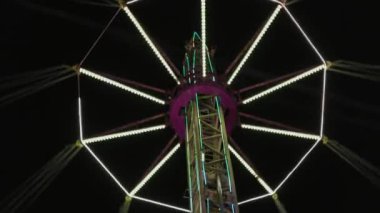 Lunaparktaki gece hayatı. Neon ışıklarıyla parlayan dönen bir cazibe. Alt manzara. Kimse..