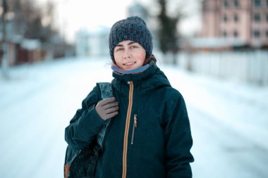 Şapka ve ceket giymiş gülümseyen beyaz bir kadının portresi. Kış mevsimi, kar yağışı.