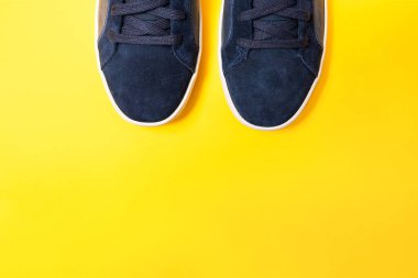 Sarı arka planda mavi deriden yapılmış bir çift yeni spor ayakkabı. Uzayı kopyala Ayak parmaklarını kapat..