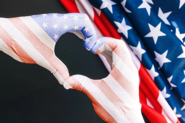 爱国心 戴手套的人的手呈美国国旗的颜色 显示出一种心动的姿态 有美国国旗的黑色背景 靠近点美国国定假日的概念 — 图库照片