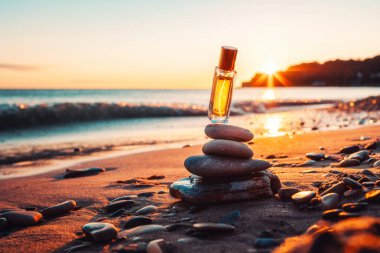 Altın kapaklı şeffaf cam parfüm şişesi bir taş piramidinin üzerinde asılı duruyor. Kumsal ve günbatımı arka planda. Uzayı kopyala Parfüm reklamcılığı konsepti.