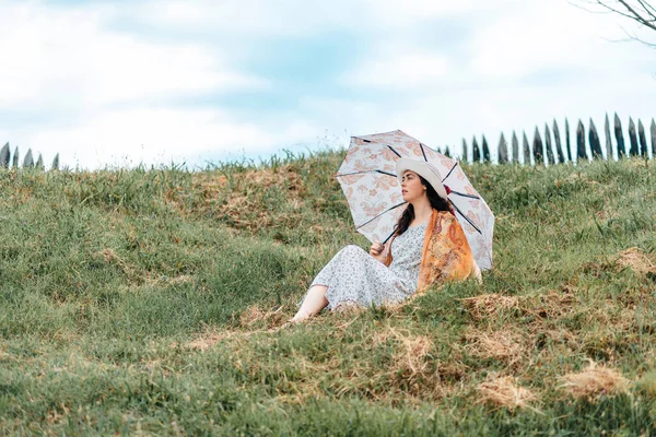 一个戴着草帽和衣服的年轻女子 拿着雨伞躺在草地上 心理和孤独的概念 — 图库照片
