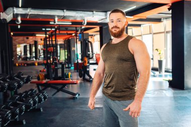 Spor salonunda poz veren yakışıklı, sakallı bir adamın portresi. Zindelik ve refah kavramı.