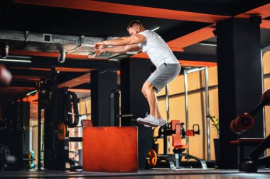 Spor salonunda Küp 'te atlama eğitimi alan sakallı genç bir adam. Yan görüş. Spor ve spor konsepti.