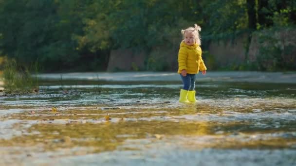 Mała Zabawna Dziewczynka Żółtych Gumowych Butach Stojąca Wodzie Nad Rzeką — Wideo stockowe