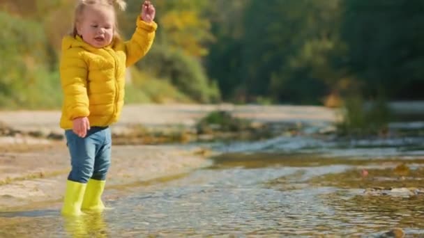 Une Petite Fille Bottes Caoutchouc Jaune Marchant Prudemment Sur Rivière — Video