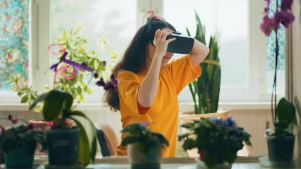 バーチャルドラムで遊んでいるVrメガネの白人女性の笑顔 屋内では 内部は自然植物で飾られています 背景に窓がある 現代技術の概念 — ストック動画