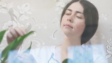 Pencere kenarında çiçek bahçesini inceleyen bir kadının portresi. Alt manzara. Çiçek ve bitki yetiştirme konsepti.