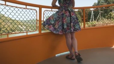 Yaz turizmi. Kanat çırpan elbiseli genç bir kadın ayakta duruyor ve etrafı geziyor. Arka görüş ve ayakları kapatın. Nehir otobüsüyle gezi kavramı.