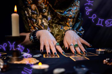 Haritacılık. Bir falcı Tarot kartları okur. Masanın üzerinde mumlar var. Eller yukarı. Zodiac daireleri görüntünün köşelerinde yer alır. Kehanet, astroloji ve ezoterizm kavramı..