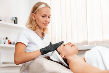 Kaldırma terapisi. Profesyonel güzellik uzmanı kuafördeki müşteriye gençleştirme yüz masajı yapıyor. Kozmetoloji kavramı.