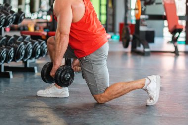 Spor salonundaki dambıllarla atletizm eğitimini tamamlayın. Çömelme egzersizi. Zindelik kavramı.