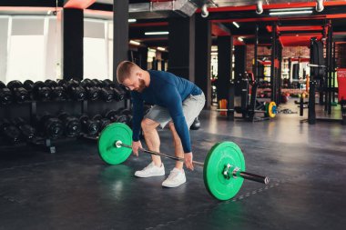 Halter çöker. Sakallı bir sporcu spor salonunda halter kaldırarak antrenman yapıyor. Zindelik kavramı.