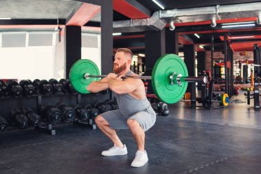 Halter çöker. Sakallı bir sporcu spor salonunda halter kaldırarak antrenman yapıyor. Çapraz eğitime ayak uydurmak.